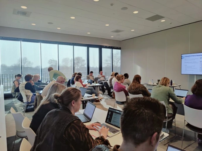 en groep collegas werkt samen op laptops tijdens een interactieve incompany AI training.