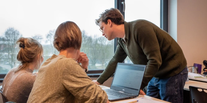 AI trainer geeft een deelnemer persoonlijke begeleiding achter de laptop tijdens een praktische cursus.